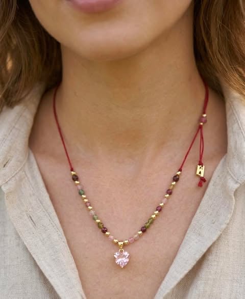 Kobieta w bordowo-złotej biżuterii z sercem z różowego kryształu