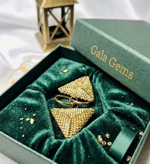 Złote trójkątne elementy biżuterii w pudle Gala Gems