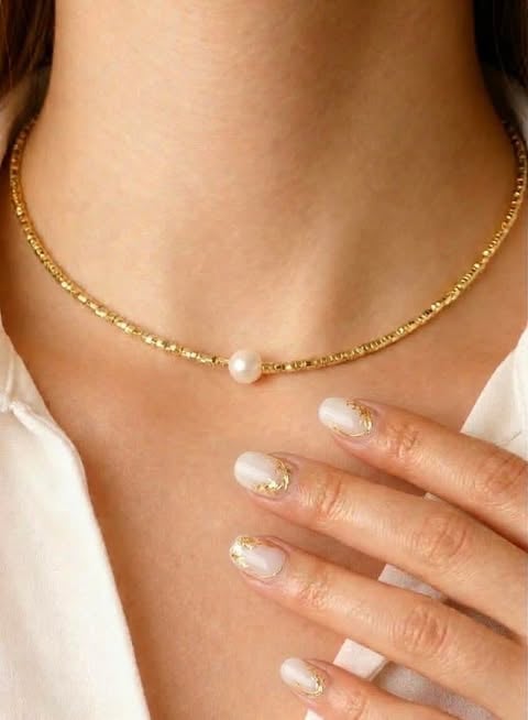 Kobieta w złotym naszyjniku z perłą