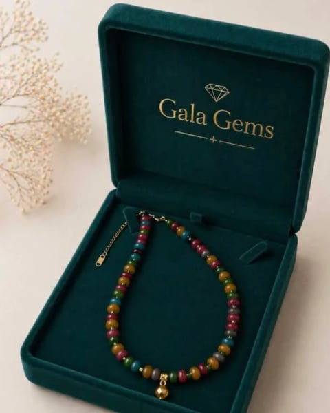 Multicolored gemstone beaded bracelet in open Gala Gems box with gold accents and dried flowers